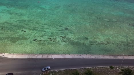 Aerial-view-over-bay-street-and-a-boat-in-shallow-waters-of-Bahamas---high-angle,-drone-shot