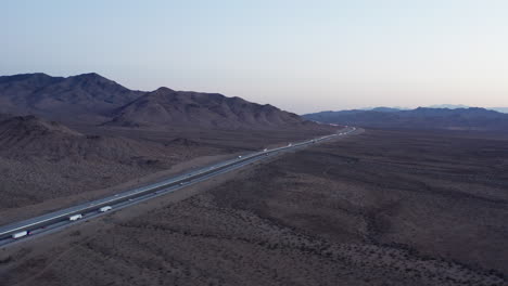 Luftaufnahme-Von-Lastwagen,-Die-Auf-Der-Autobahn-Durch-Die-Kalifornische-Wüstenlandschaft-Fahren