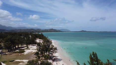 4K-cinematic-crane-drone-shot-revealing-Kailua-Beach-and-the-crystal-clear-ocean-water-in-Oahu-from-behind-a-tree