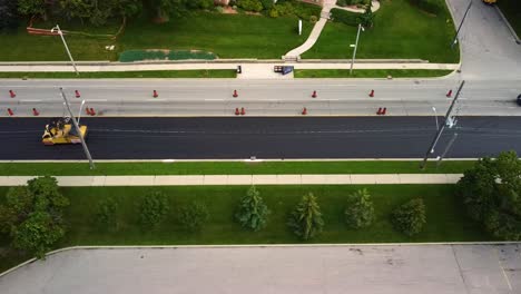 Drone-shot-of-roller-smoothing-out-new-asphalt-on-a-city-street