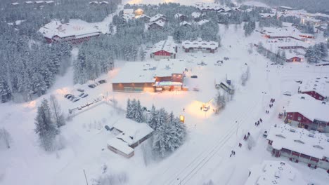 Drone-aerial-tilt-down,-Levi,-Finland-with-bus-and-pedestrians-on-road-ski-village