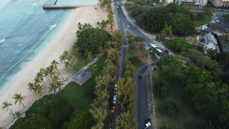 4k-Filmische-Drohnenaufnahme,-Die-Unserem-Auto-Folgt,-Während-Es-Neben-Dem-Waikiki-Beach-Und-In-Den-Queen-Kapi&#39;olani-Park-In-Oahu-Fährt
