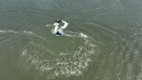 An-aerial-view-over-Gravesend-Bay-in-Brooklyn,-NY-as-two-jet-ski-riders-enjoys-the-beautiful-day