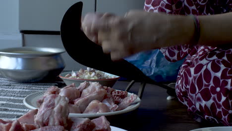 Close-up-hands-of-women-slicing-the-raw-chicken-meat-into-small-pieces-on-Eid-al-Adha
