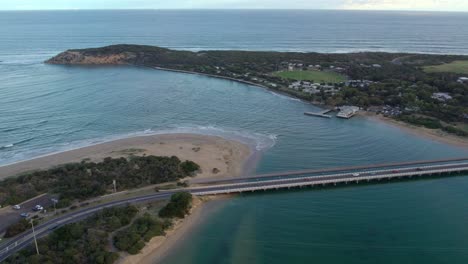 Aerial-footage-looking-downstream-near-the-mouth-of-the-Barwon-River-at-Barwon-Heads,-Victoria,-Australia
