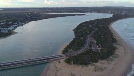Reverse-drone-footage-looking-upstream-near-the-mouth-of-the-Barwon-River-at-Barwon-Heads,-Victoria,-Australia