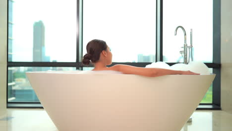 Back-View-of-Sexy-Woman-in-Luxury-Bathtub-in-Front-of-Windows-With-Cityscape-View