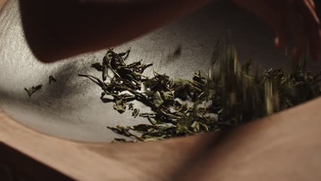 Asian-woman-hands-stir-green-tea-leaves-on-traditional-firing-pan