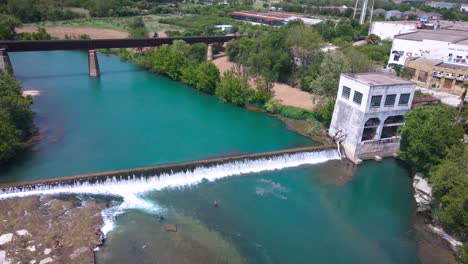 Drone-footage-over-the-Guadalupe-River-near-the-Faust-Street-bridge-in-New-Braunfels,-Texas-with-the-River-Mill-and-dam-in-the-background