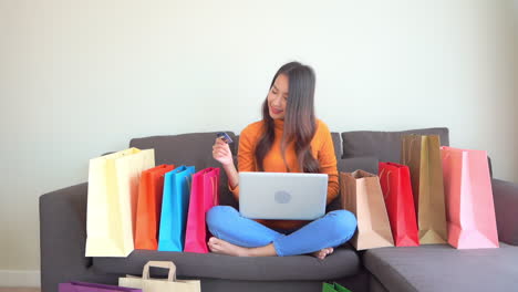 Schöne-Asiatische-Frau,-Die-Online-Von-Zu-Hause-Aus-Mit-Laptop-Und-Bankkreditkarte-Einkauft---Vollbild