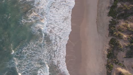 Vertical-slow-moving-drone-footage-of-waves-hitting-the-beach-at-Point-Lonsdale,-Victoria,-Australia