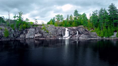 Flowing-rocky-waterfall-and-scenic-lake-landscape-with-cliff-lookout-High-Falls-Muskoka-Ontario