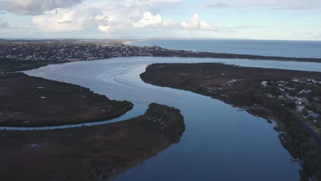 Aerial-footage-looking-downstream-near-the-mouth-of-the-Barwon-River-near-Barwon-Heads-and-Ocean-Grove,-Victoria,-Australia