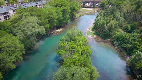 Drone-footage-over-the-Guadalupe-River-near-the-Faust-Street-bridge-in-New-Braunfels,-Texas-with-Interstate-35-in-the-background