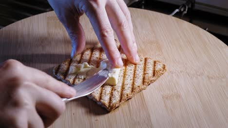 Hands-Spread-Melted-Cheese-On-A-Slice-Of-Whole-Grain-Toast
