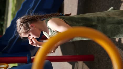 VERTICAL-VIDEO:-Young-girl-playing-plastic-drums-in-a-children’s-playground-with-sticks