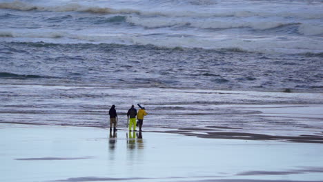 Three-men-walking-on-the-beach-toward-the-surf