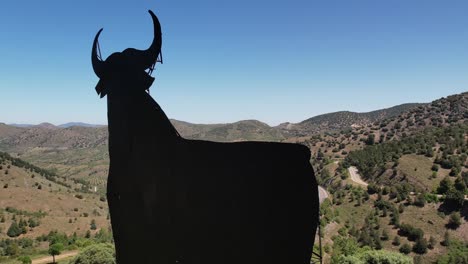 Aerial-view-of-Toro-de-Osborne,-a-spanish-symbol,-huge-metal-bull-on-the-top-of-a-hill,-daylight