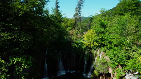 Aerial-Pedestal-Down-In-Between-Forest-Trees-To-Reveal-Cascading-Waterfalls-At-Plitvice-Lakes,-Croatia