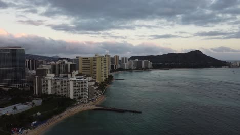 4K-Filmische-Drohnenaufnahme-Gegen-Den-Uhrzeigersinn-Von-Waikiki-Beach-Und-Diamond-Head,-Während-Die-Sonne-In-Oahu-Untergeht