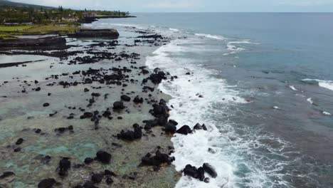 4K-cinematic-close-up-drone-shot-of-waves-crashing-on-lava-rock-and-the-reef-on-the-Kona-Coast-of-the-Big-Island-of-Hawaii-on-a-cloudy-day