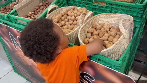 Zweijähriges-Afrikanisches-Kind,-Das-Nüsse-In-Einem-Supermarkt-Zählt