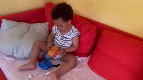 Cute-two-year-afro-european-child-happy-playing-with-Mr-Potato-at-home