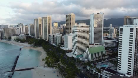 4k-Filmische-Drohnenaufnahme-Von-Waikiki-Beach-Und-Den-Hotels,-Die-Ihn-Bei-Sonnenaufgang-An-Einem-Bewölkten-Tag-In-Oahu-Säumen