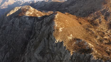 drone-flyover-on-rocky-mountains-and-escarpments-of-Kotor-bay,-Montenegro,-on-late-afternoon