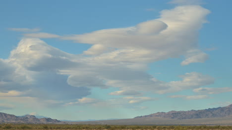 Unique-beautiful-scenic-white-clouds-in-blue-sky-over-California-desert-landscape,-zoom-in-shot