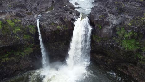 4K-cinematic-crane-drone-shot-of-a-waterfall-raging-over-a-cliff-in-a-rainforest-near-Hilo-on-the-Big-Island-of-Hawaii