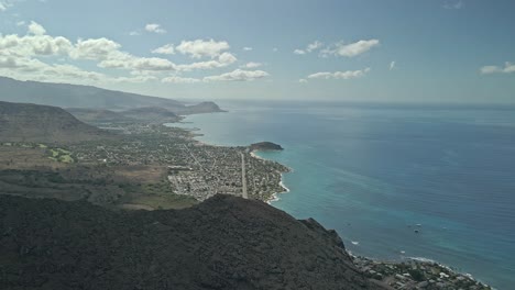 Vista-Aérea-Ascendente-De-La-Montaña-Que-Revela-La-Comunidad-Frente-A-La-Playa-Hawaiana