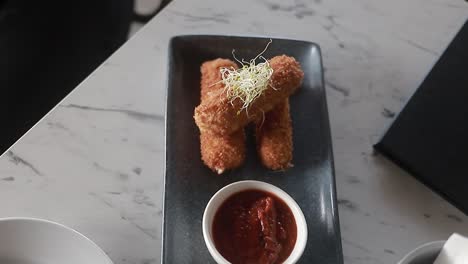 dish-of-croquettes-on-thin-plate-with-its-ketchu-on-the-side,-restaurant-food