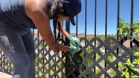 Hispanic-female-repairs-metal-fence-at-her-home