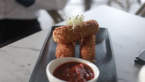 croquettes-on-a-thin-plate-with-its-ketchu-on-the-side,-restaurant-food,-video-detail