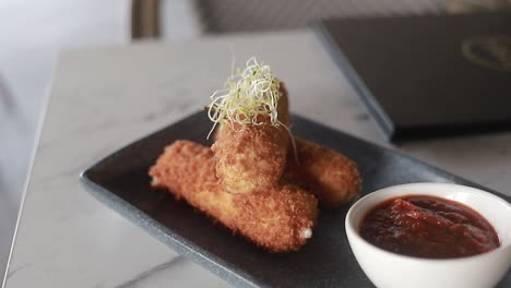 dish-of-croquettes-on-thin-plate-with-its-ketchu-on-the-side,-restaurant-food,-video-HD