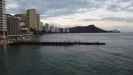 4K-cinematic-zoom-drone-shot-of-people-watching-the-sunset-on-the-rocks-near-Waikiki-Beach-with-Diamond-Head-in-the-background