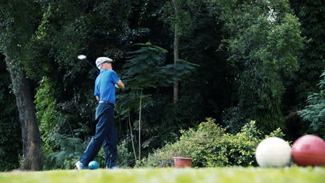 Elderly-Asian-man-with-a-perfect-swing-teeing-off-at-the-green-at-Changi-Golf-Club-in-Singapore-in-a-tropical-setting