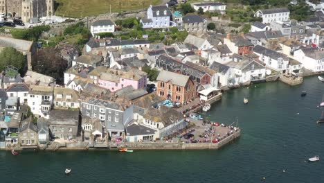 Rising-aerial-view-of-toursists-congregated-at-Fowey-Harbour,-on-the-banks-of-the-River-Fowey-in-Cornwall,-UK