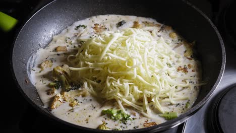 Agregando-Queso-Mozzarella-Y-Harina-A-La-Salsa-Para-Pasta-Cocinando-En-Una-Sartén