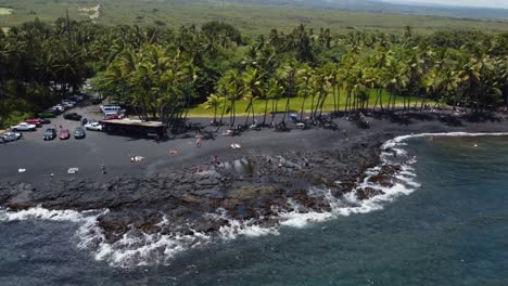 4K-cinematic-drone-shot-revealing-waves-crashing-on-Punulu'u-Black-Sand-Beach-on-a-sunny-day-on-the-Big-Island-of-Hawaii