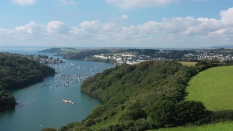 Wide-aerial-sliding-shot-over-the-landscape-surrounding-the-River-Fowey,-Revealing-the-Cornish-town-of-Fowey-in-Cornwall,-UK