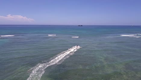 Aerial-view-of-surfer-getting-towed-out-to-sea-by-jet-skier-in-Oahu