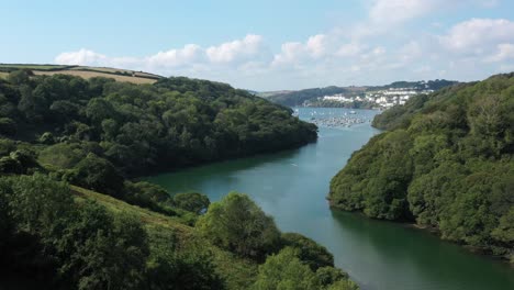 Low-aerial-view-flying-along-the-River-Fowey,-in-Cornwalls-Area-of-Outstanding-Natural-Beauty-towards-Fowey-town
