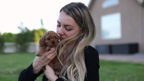 Blonde-Woman-Holding-and-Cuddling-a-Cute-Goldendoodle-Puppy-Dog