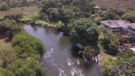 Aerial-view-of-paddle-boarders-enjoying-a-leisurely-ride-along-river