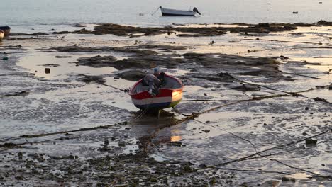 Single-boat-stranded-on-ground-during-low-tide-at-sunset