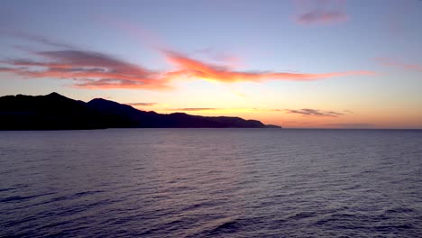 Ruhige-Und-Entspannende-Aussicht-Auf-Das-Meer-Bei-Sonnenuntergang-Mit-Bergsilhouette-Im-Hintergrund