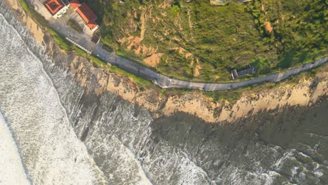 Aerial-view-of-drone-flying-above-beautiful-coast-with-views-of-ocean-waves-and-water-crashing-on-to-sandy-coast