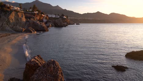 Soft-and-calm-scenery-at-beach-in-Nerja,-Spain-with-ocean-and-cliffs-in-distance